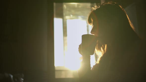 Silhouette of a Pretty Woman Drinking Coffee Early in the Morning Enjoying Morning Coffee