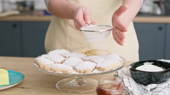 Video of woman sprinkling and decorating cookies with powdered sugar alt
