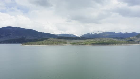 Aerial Flyby Shot of a Lone Sailboat on a Beautiful Mountain Lake in Colorado (Dillon Reservoir) alt