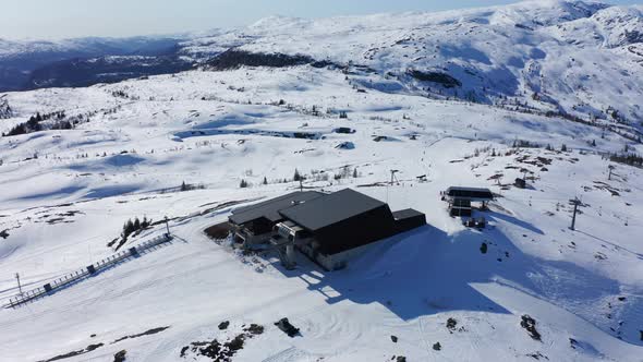 Descending tilt up aerial showing Ski-lift and gondola station with restaurant on top of mount Hangu alt