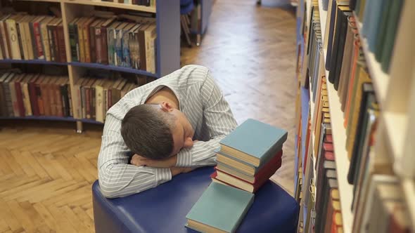 The tired student fell asleep in the library. alt