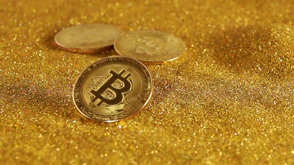 Bitcoin Falls on a Table With a Pile of Golden Sand
