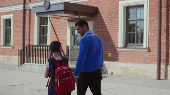 Back View of Father Leads Little Child Schoolgirl in First Grade