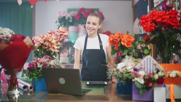 Female Florist Discusses the Order By Talking on Video Call Using a Laptop and Screen Tablet alt