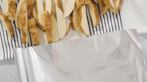 Flat lay. Step by step. Preparing russet potatoes in wedges with olive oil and spices to bake in the alt
