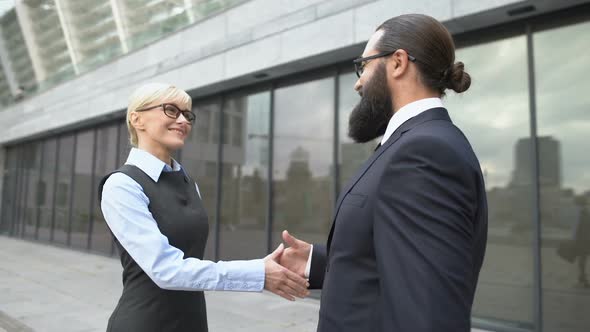 Male and Female Colleagues Shaking Hands in Street, Business Cooperation Meeting