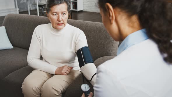 Back View of Unknown Female Doctor Measuring Blood Pressure of Aged Woman and Saying Her That It is alt
