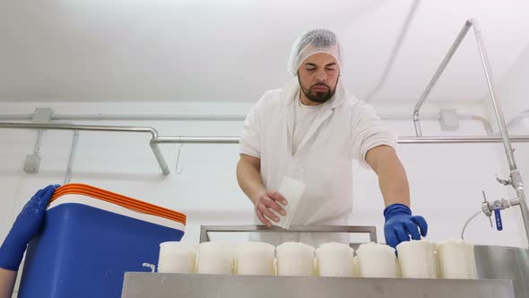 diary man passing the cheese into the molds - Cheese production alt