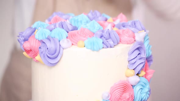 Step by step. Pastry chef piping butter cream frosting on unicorn cake for little girl birthday part alt