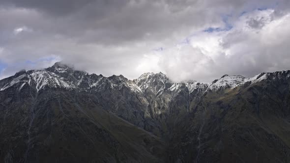 Clouds moving above epic mountain peaks alt