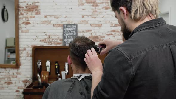 Man Barber Cutting Hair of Male Client with Clipper at Barber Shop alt