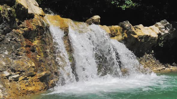 Closeup of Water Stream Flowing Down From the Cascade on a Bright Sunny Day alt