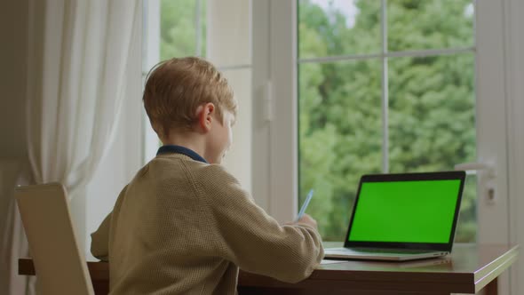 School Boy Talking to Laptop Green Screen Sitting at Home alt