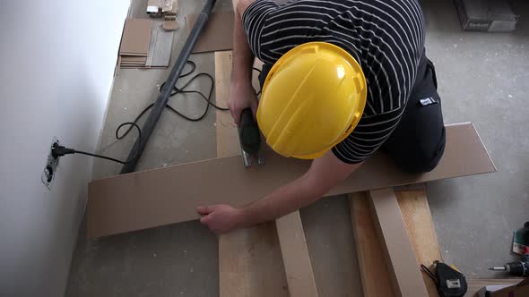 Man Working with Jigsaw and Wooden Laminate Floor Panels