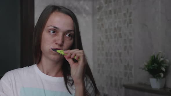 Young Woman is Brushing Her Teeth with a Toothbrush in Bathroom