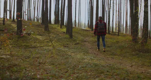 Young Man with Backpack Walking on the Hill Against the Mountains at Sunset in Autumn. Landscape alt