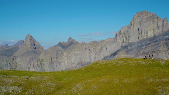Aerial reveal and orbit around hikers, Grand Muveran massif and the Alps in the background, Switzerl alt