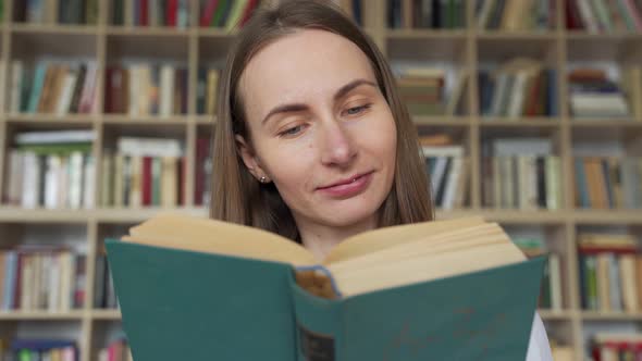 Young Woman Student Reading a Book in a Library alt