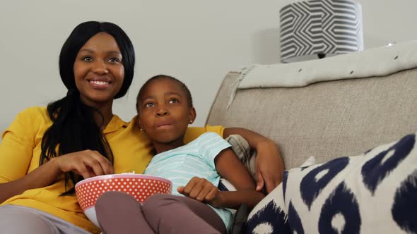 Mother and daughter watching television in living room 4k alt