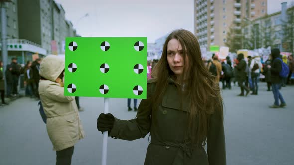 Banner in a Crowd of People Copy Space Text. Girl with a Blank Poster on Strike. alt