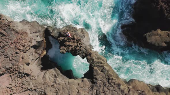 Man Stands on the Edge of the Rock As Seen From the Top alt