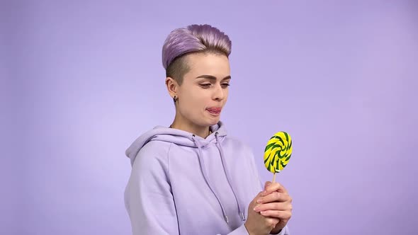 Young Woman in Purple Holding Lollipop Licking Lips Wanting Eat Candy alt