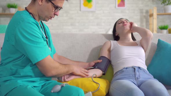 Male Doctor Measures a Young Woman's Blood Pressure with a Tonometer Close Up alt