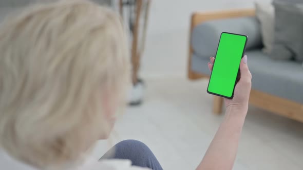 Rear View of Senior Old Woman Looking at Smartphone with Chroma Key Screen on Yoga Mat alt
