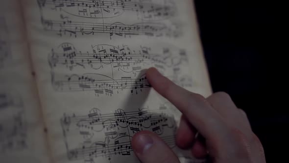 Hand Pointing at Musical Notes on Vintage Sheet Music, Classical Score alt