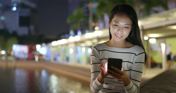 Woman looking at mobile phone at night  alt