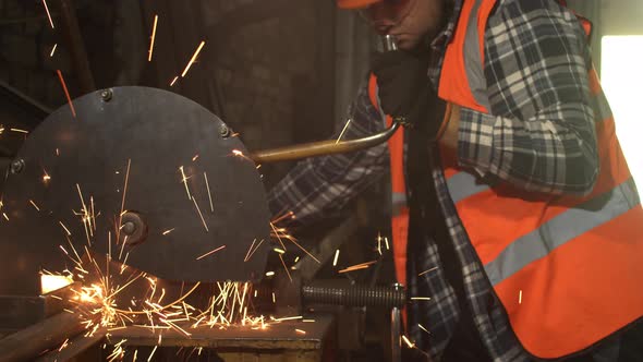 Male Worker Cutting Metal in Grungy Workshop