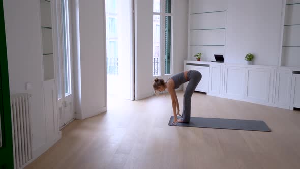 Flexible woman doing yoga on mat at home alt