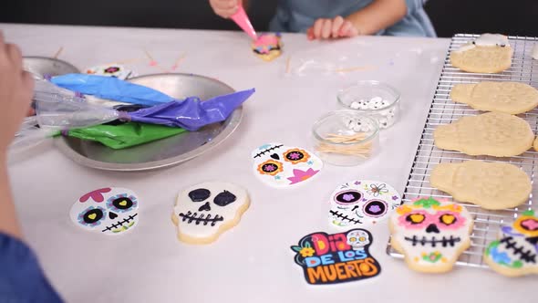 Step by step. Mother and daughter decorating sugar skull cookies with royal icing for Dia de los Mue alt