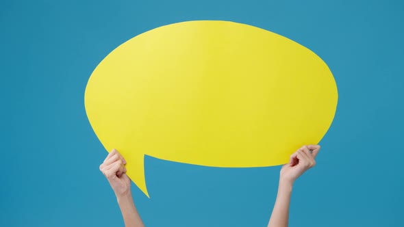 Young teen girl holding with copyspace cartoon speech bubble in hand over blue background.