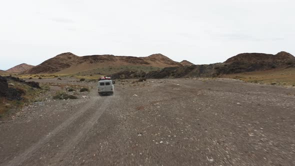 Offroad Vehicle Goes on a Dirt Road Among the Mountains alt