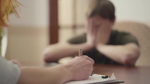 Depressed Young Man Sitting in the Office of Psychologist, Telling Her About His Problems. Female alt