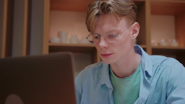 Young Man Actively Typing and Looking at the Laptop Working From Home alt
