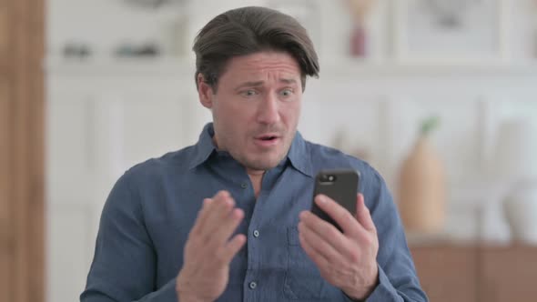 Portrait of Young Man Reacting to Loss on Smartphone alt