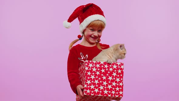 Girl in Christmas Red Sweater Hat Smiling Unwrapping Gift Opening Box with Pet Cat Great Surprise alt