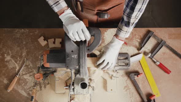 Top View of Carpenter Holding Plank Near Circular Saw in Carpentry Shop alt