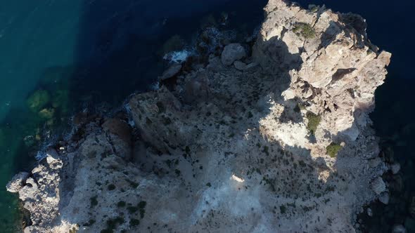 Overhead Top Down Aerial of Generic Mountain Coast with Turquoise Water and Waves Crashing on Rocks alt
