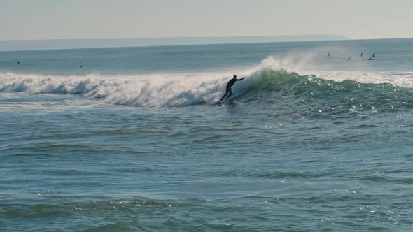 Surfer catching blue waves of the Atlantic Ocean on a beautiful sunny day alt