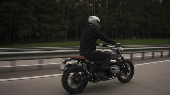 Man Riding Scrambler Motorbike on the Highway Through the Autumn Forest