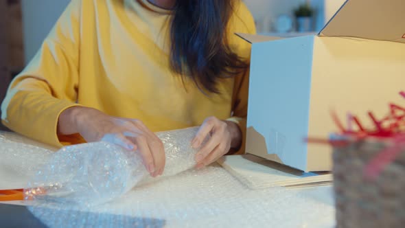 Young Asia businesswoman packing glass use bubble wrap for packing support damage fragile product