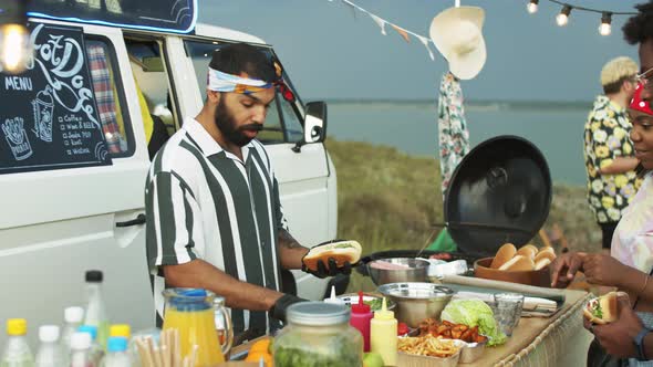 Food Truck Seller Preparing Hot Dogs and Talking with Customers alt