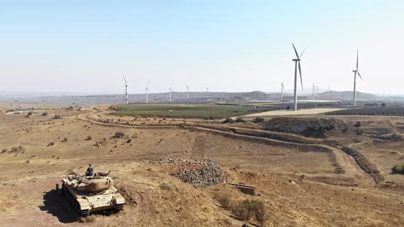 drone view of man meditating on tank in front of wine turbine wide shot