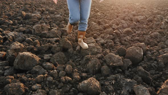 Farmer in Rubber Boots Walking on a Dry Plowed Field, Close-up alt