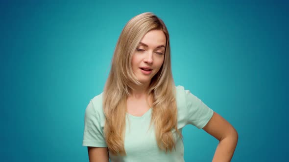 Young Woman Pointing Fingers Down Showing Copy Space Against Blue Background alt