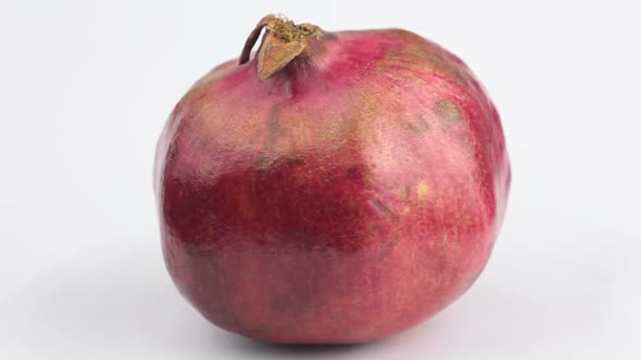 Ripe Juicy Pomegranate Rotates on a White Background