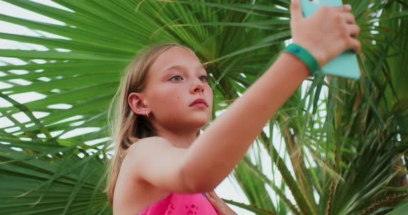 Teen Girl is Making Selfie Under Palm Tree During Her Tropical Vacations
